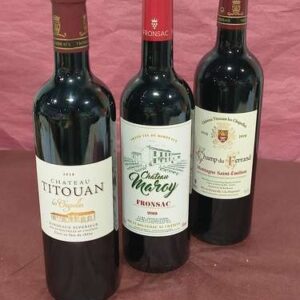 Trois bouteilles de vin rouge sur fond rose : Château Titouan 2019 Bordeaux Supérieur, Château Maroy 2019 Fronsac et Champ du Ferrand Montagne Saint-Émilion.