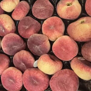 Plateau de pêches fraîches variées: rondes, plates, rouges et jaunes orangées. Un assortiment juteux de fruits mûrs.