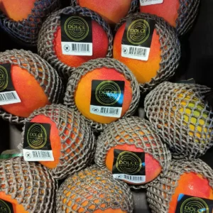 Mangues Dolce Imperiale emballées dans un filet protecteur. Fruits exotiques mûrs avec étiquettes noires et code-barres.
