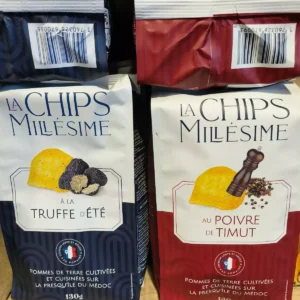 Deux paquets de chips La Chips Millésime : l'un bleu à la truffe d'été, l'autre rouge au poivre de Timut. Pommes de terre du Médoc, 130g.