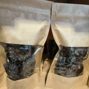 Plusieurs sachets de pruneaux secs emballés dans du papier kraft et du plastique transparent, prêts à la vente.