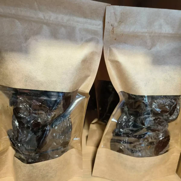 Plusieurs sachets de pruneaux secs emballés dans du papier kraft et du plastique transparent, prêts à la vente.