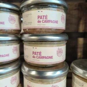 Pots de pâté de campagne pur porc de la marque Fiers de nos Terres, empilés sur une étagère. Étiquettes blanches avec texte rose.