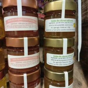 Deux piles de petits pots de gelée safranée : pamplemousse bio sur la gauche et citron bio sur la droite. Chaque pot pèse 100g.