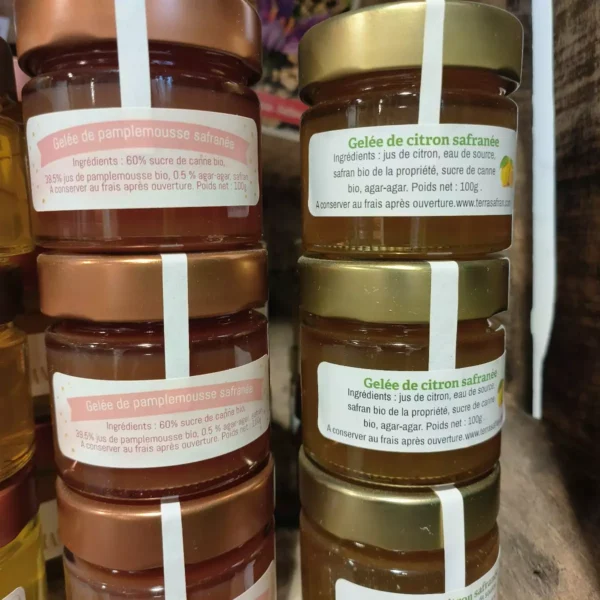 Deux piles de petits pots de gelée safranée : pamplemousse bio sur la gauche et citron bio sur la droite. Chaque pot pèse 100g.