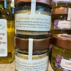 Deux pots de Gomasio au safran bio de 50g (sésame, sel, safran de Nérigean) sont au premier plan, prêts à saupoudrer. Autres produits au safran en arrière-plan.