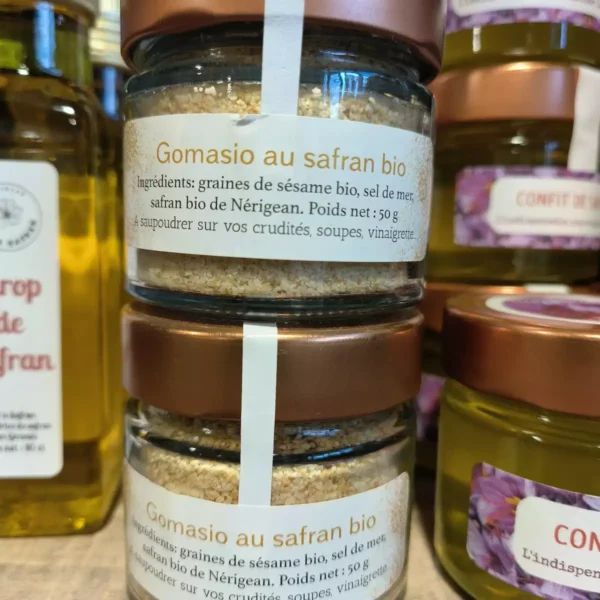 Deux pots de Gomasio au safran bio de 50g (sésame, sel, safran de Nérigean) sont au premier plan, prêts à saupoudrer. Autres produits au safran en arrière-plan.