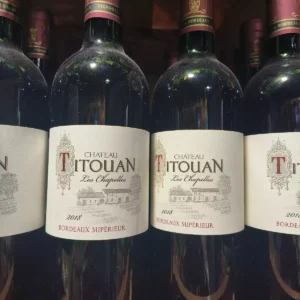Bouteilles de vin rouge poussiéreuses CHATEAU TITOUAN Les Chapelles 2018 Bordeaux Supérieur, alignées.
