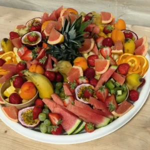 Grande assiette de fruits frais coupés: pastèque, fraises, raisins, orange, ananas, fruit de la passion, pamplemousse, kiwi, bananes. Présentation colorée.