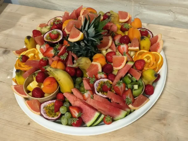 Grande assiette de fruits frais coupés: pastèque, fraises, raisins, orange, ananas, fruit de la passion, pamplemousse, kiwi, bananes. Présentation colorée.