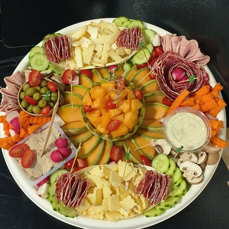 Vaste plateau apéritif avec fromages, salami, melon frais, olives, crudités (carottes, radis, concombres) et trempette.