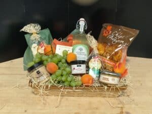 Panier garni de produits gourmands français : boisson Finesse des Vergers, Chips d'Aveyron, Perles Céréales, terrine, sauce Roquefort, fruits.